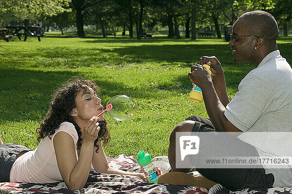 Junges Paar im Park bläst Seifenblasen