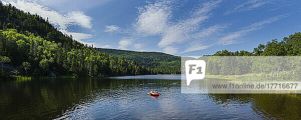 Paddling an inflatable boat down the tranquil river at Tadoussac; Tadoussac  Quebec  Canada