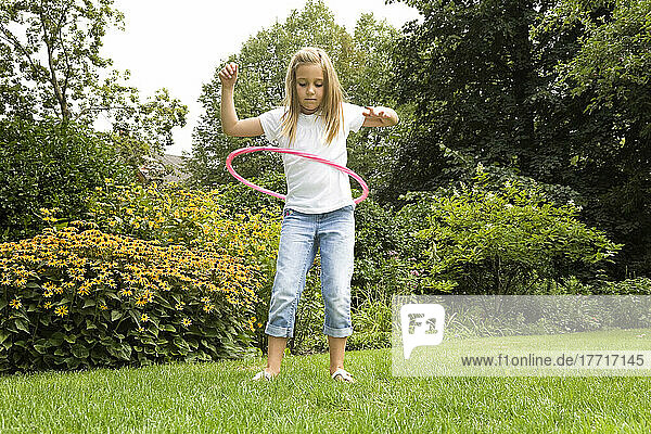 Young Girl Playing With Her Hula Hoop In The Garden; Ontario Canada
