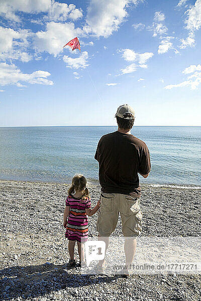 Father And Daughter Flying A Kite By Lake Ontario; Ontario Canada