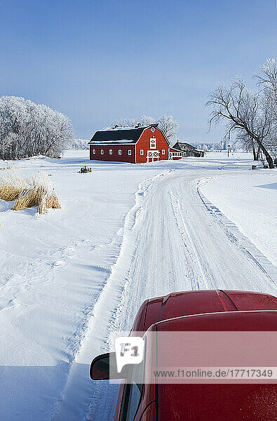 Lastwagen entlang Landweg mit roten Scheune im Hintergrund im Winter  in der Nähe von Oakbank  Manitoba