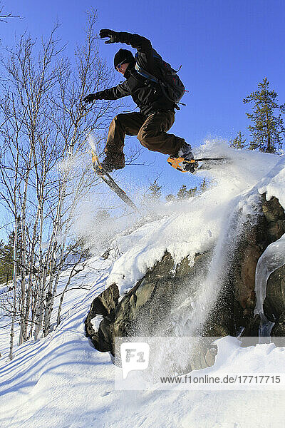 Mann springt in Schneeschuhen von einem Felsen  Abitibi-Temiscamingue  Quebec
