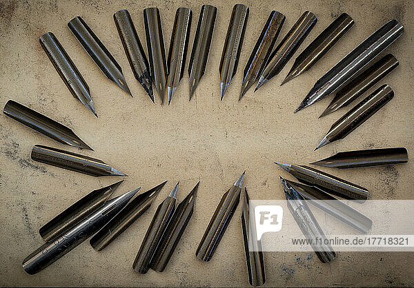 Numerous pen nibs displayed in a circular formation on a counter  some stained with ink; Studio