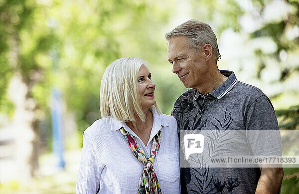 Outdoor portrait of a mature couple in a park as they stand and look at each other; Edmonton  Alberta  Canada