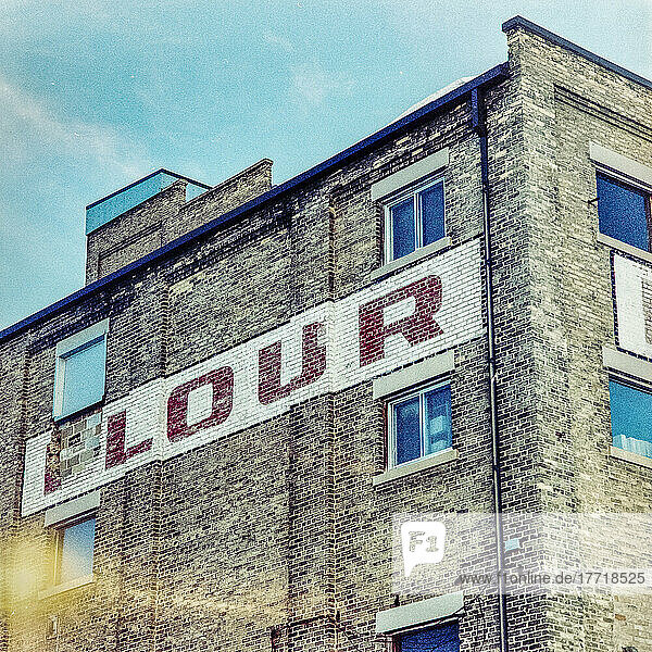 Heritage building with the word 'Flour' painted on the brick wall  Five Roses Flour Mill  Ogilvie Mills Ltd; Winnipeg  Manitoba  Canada