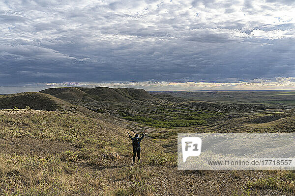 Frau steht mit erhobenen Armen vor einer schönen Aussicht im Grassands National Park; Val Marie  Saskatchewan  Kanada