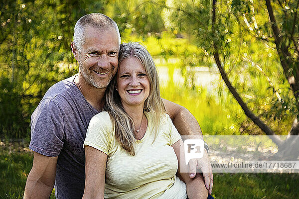 Outdoor portrait of a mature married couple sitting on the grass in a park; Edmonton  Alberta  Canada
