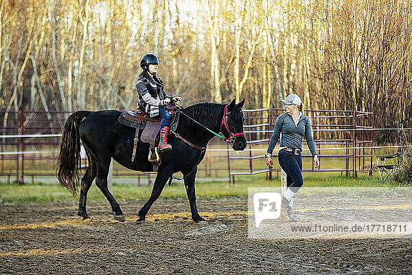 A trainer working with a young girl with Cerebral Palsy during a Hippotherapy session; Westlock  Alberta  Canada