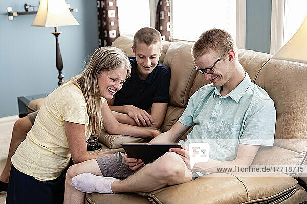 Mutter und junge erwachsene Brüder benutzen gemeinsam ein Tablet zu Hause; Edmonton  Alberta  Kanada