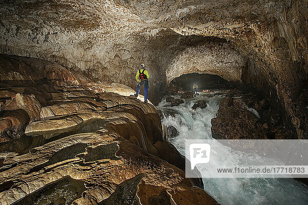 Mitglieder eines Erkundungsteams stehen an einem reißenden Fluss in der Ora-Höhle  während sie die wilden und gefährlichen Flusshöhlen der Nakanai-Berge auf der Insel Neubritannien  Papua-Neuguinea  erforschen; Neubritannien  Papua-Neuguinea