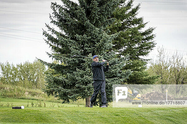Amputee with one arm prosthesis taking a swing on the golf course; Okotoks  Alberta  Canada