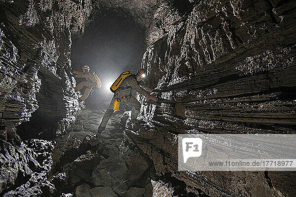 Zwei Forscher klettern entlang einer Querung über einem kleinen Wasserbecken in der Veryovkina-Höhle. Die einzigen Haltegriffe sind kleine Vorsprünge in den kleinen Kalksteinschichten. Während des Hochwassers  das die Höhle eine Woche nach der Aufnahme dieses Fotos überflutete  füllte sich die gesamte Höhle bis zur Decke mit Wasser; Gagra  Kaukasus  Abchasien