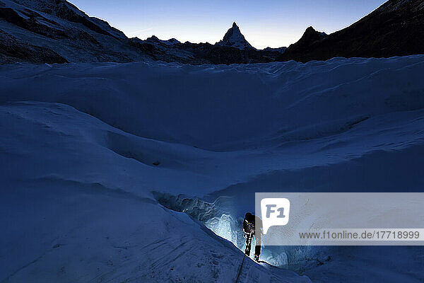 British cave explorer and glaciologist emerges from a moulin with the Matterhorn in the background.