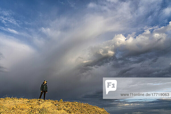 Dramatische Wolkenformation am Himmel hinter einer Frau auf einem Bergrücken im Grasslands National Park  Saskatchewan  Kanada; Val Marie  Saskatchewan  Kanada