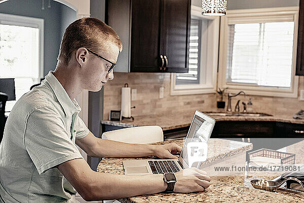 Young man uses a laptop computer at home; Edmonton  Alberta  Canada
