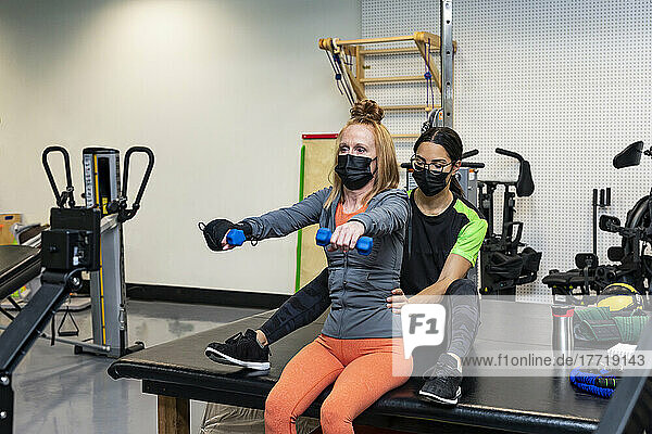A paraplegic woman doing bilateral raises during her workout with her trainer: Edmonton  Alberta  Canada