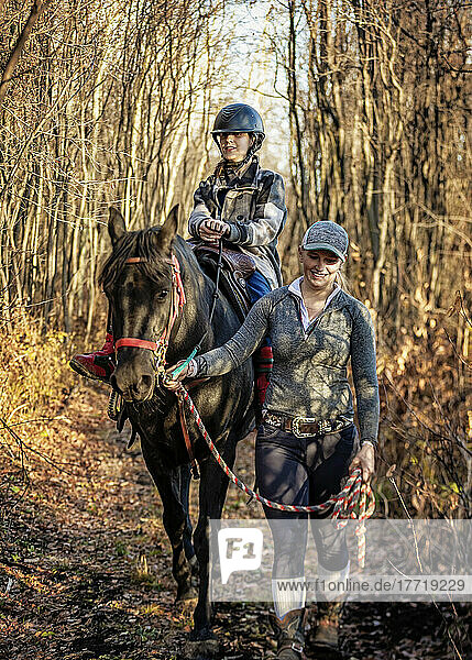 A young girl with Cerebral Palsy and her trainer working with a horse on a trail ride during a Hippotherapy session; Westlock  Alberta  Canada