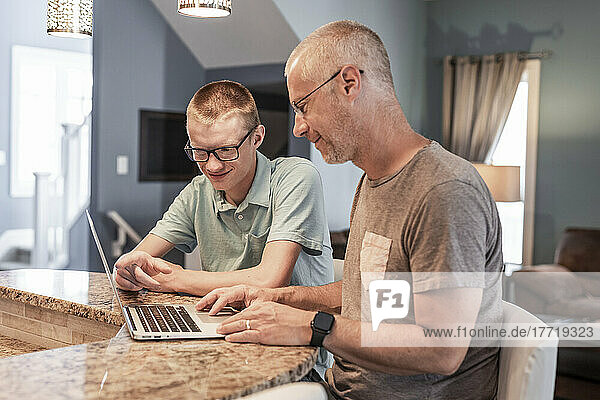 Vater und Sohn benutzen gemeinsam einen Laptop zu Hause; Edmonton  Alberta  Kanada