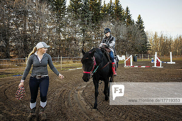 A young girl with Cerebral Palsy and her trainer working with a horse during a Hippotherapy session; Westlock  Alberta  Canada