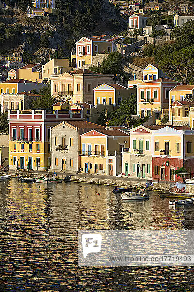 Warmes Sonnenlicht auf den farbenfrohen Gebäuden entlang der Uferpromenade im Hafen von Gialos  Insel Symi (Simi); Dodekanes-Inselgruppe  Griechenland