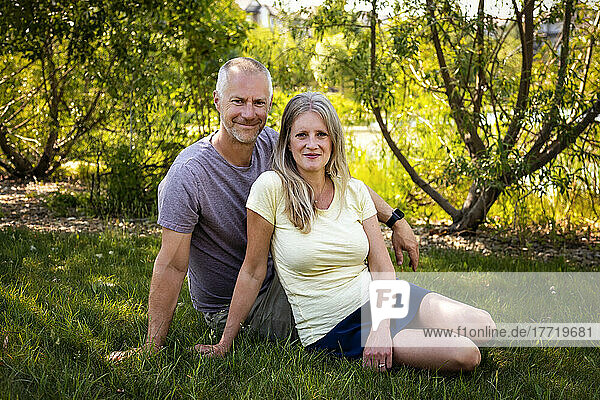 Outdoor portrait of a mature married couple sitting on the grass in a park; Edmonton  Alberta  Canada