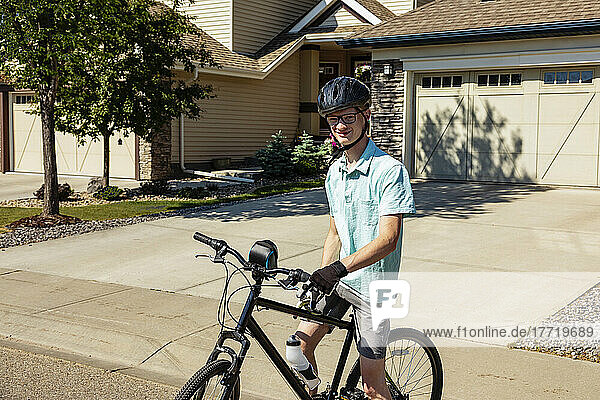 Junger Mann posiert auf seinem Fahrrad in einer Wohnstraße; Edmonton  Alberta  Kanada