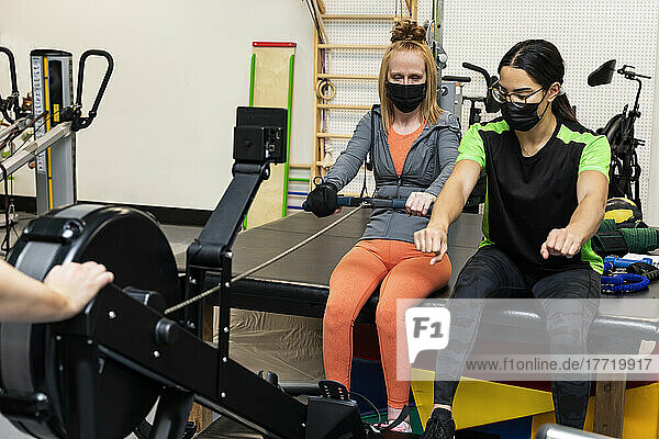 Eine querschnittsgelähmte Frau trainiert mit ihren Trainern an einem Rudergerät; Edmonton  Alberta  Kanada