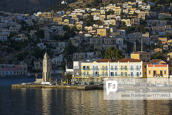 Symi Clock Tower and sunlit buildings on the waterfront at Gialos Harbor  Symi (Simi) Island; Dodecanese Island Group  Greece