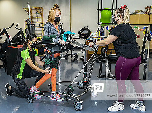 Eine querschnittsgelähmte Frau trainiert mit ihren Trainern an einem unterstützten Gehgerät; Edmonton  Alberta  Kanada