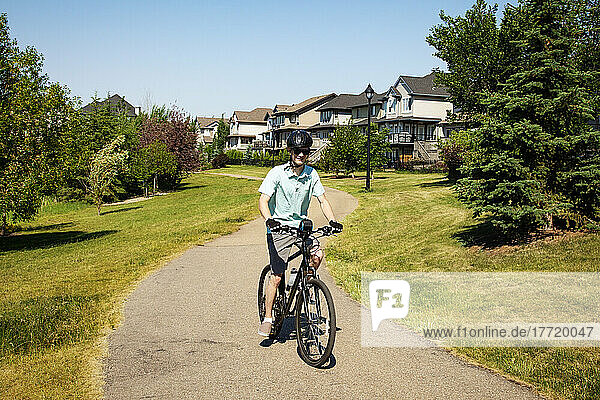 Junger Mann fährt mit seinem Fahrrad einen Weg in einem Wohnpark hinunter; Edmonton  Alberta  Kanada