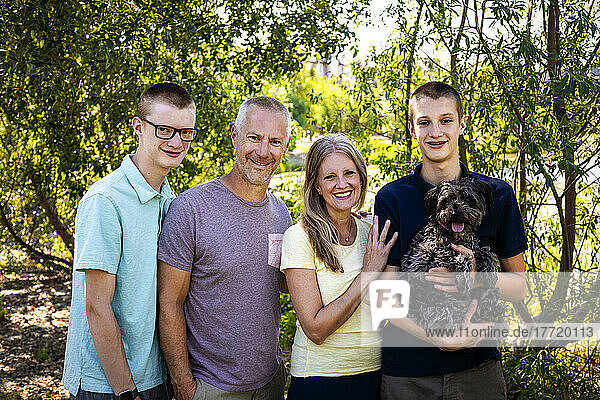 Outdoor family portrait in a park with two teenage sons and a dog; Edmonton  Alberta  Canada