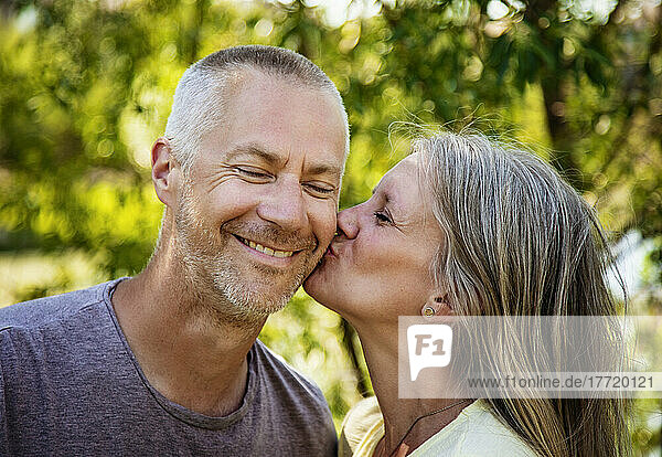 Porträt eines reifen Paares im Freien mit einer Frau  die die Wange ihres Mannes küsst; Edmonton  Alberta  Kanada