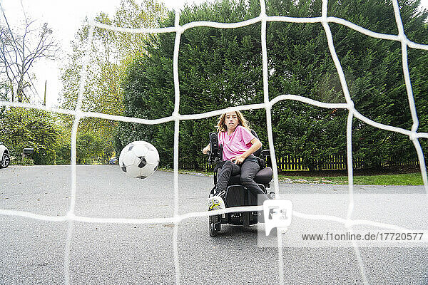 Eleven year old girl with Ullrich Congenital Muscular Dystrophy plays soccer in her wheelchair near her home; Cabin John  Maryland  United States of America