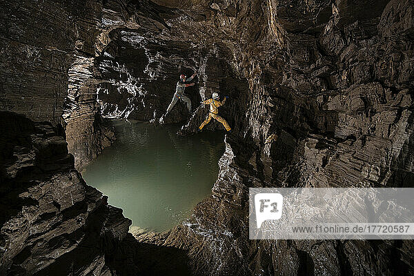 Zwei Forscher klettern um eine tiefe Wasserlache in einem Seitengang abseits des Hauptwegs in der Veryovkina-Höhle. Während des Hochwasserimpulses  der eine Woche nach der Aufnahme dieses Fotos durch die Höhle floss  füllte sich der gesamte Gang bis zur Decke mit Wasser; Gagra  Kaukasus  Abchasien