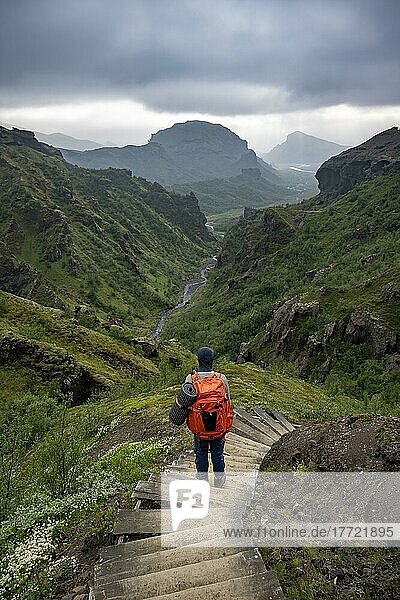 Wanderer auf Wanderweg mit Stufen  Berglandschaft mit Flusstal  hinten Bergtal mit Fluss Krossá und Berg Valahnúkur  vulkanische Landschaft am Wanderweg Fimmvörðuháls  Þórsmörk Nature Reserve  Suðurland  Island  Europa