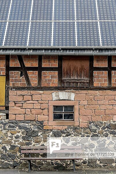 Historisches Bauernhaus mit Photovoltaikanlage  Solarpanele auf dem Dach  Hauswand mit unterschiedlich gestückeltem Mauerwerk aus Ziegelstein  Sandstein  Feldstein und Fachwerk  davor Sitzbank  Nidda  Hessen  Deutschland  Europa