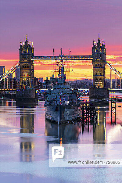 Tower Bridge and HMS Belfast reflecting in a still River Thames at sunset  London  England  United Kingdom  Europe