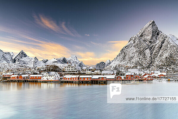 Winter sunset over snowcapped mountains and Sakrisoy village by the frozen sea  Reine  Nordland  Lofoten Islands  Norway  Scandinavia  Europe