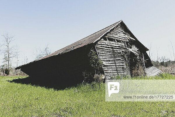 Abandoned barn leaning and near to collapse in a field.