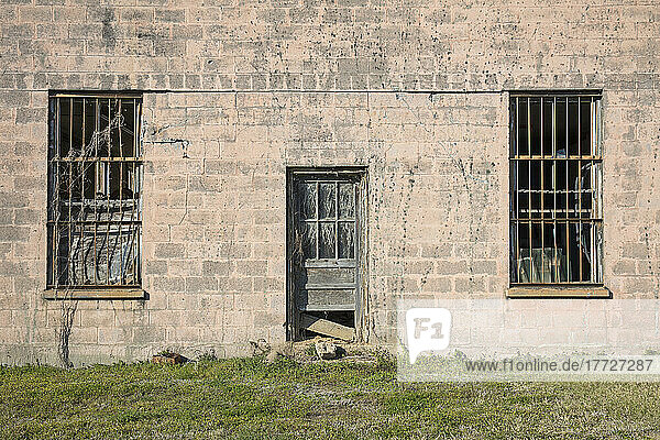 Abandoned jailhouse facade  an empty building with barsont the windows.