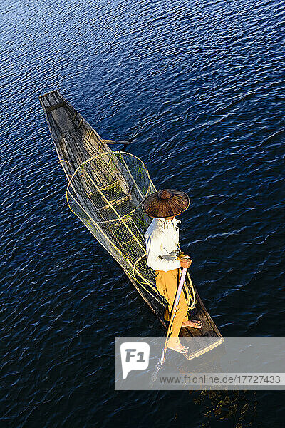 An Intha fisherman on Lake Inle on a traditional boat ith fishing nets  overhead view.
