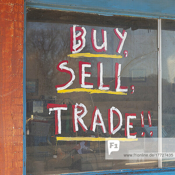 Buy Sell Trade sign in on old storefront window.