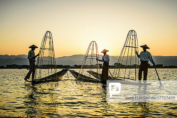 Drei Fischer fischen auf dem Inles-See mit traditionellen kegelförmigen Netzen.