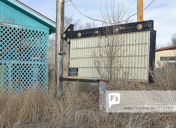 Arrow and blank sign in front of abandoned roadside store.