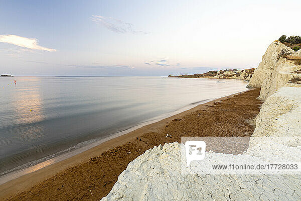 Calm sea at dawn framed by limestone cliffs overlooking the gold sand of Xi beach  Kefalonia  Ionian Islands  Greek Islands  Greece  Europe