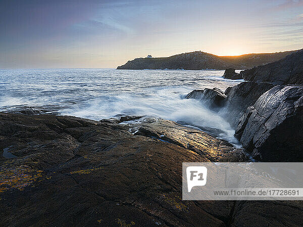 Sunrise over a bay with waves coming through the camera  Brittany  France  Europe