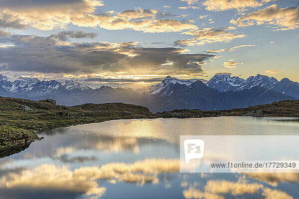 The sun and clouds is reflected in the Arcoglio Lake at sunrise  Valmalenco  Valtellina  Lombardy  Italy  Europe