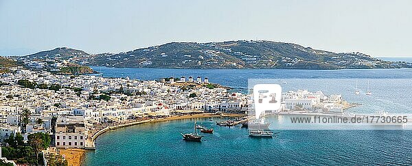 Blick auf Mykonos Stadt Griechisch touristischen Urlaubsziel mit berühmten Windmühlen  und Hafen mit Booten und Yachten bei Sonnenuntergang  Mykonos  Kykladen-Inseln  Griechenland. Mit horizontalem Kameraschwenk