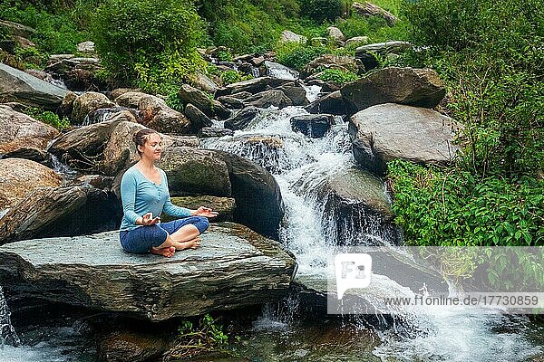 Frau macht Yoga Meditation Asana Padmasana Lotus Pose im Freien an tropischen Wasserfall