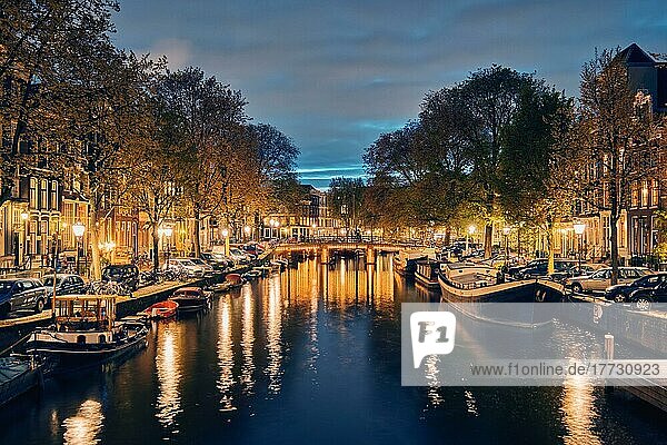 Nachtansicht der Stadt Amsterdam mit Gracht  Brücke und mittelalterlichen Häusern in der Abenddämmerung beleuchtet. Amsterdam  Niederlande  Europa